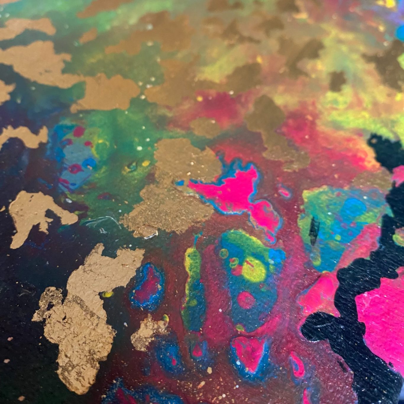 Farbenfrohe, abstrakte Oberfläche mit goldenen, pinken und blauen Mustern.